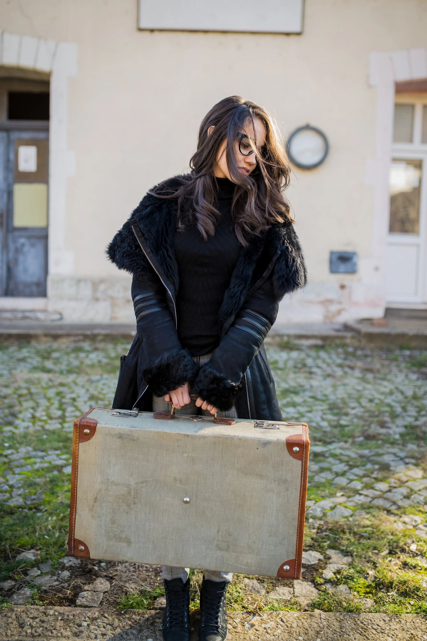 Stylish woman traveler holding a vintage suitcase